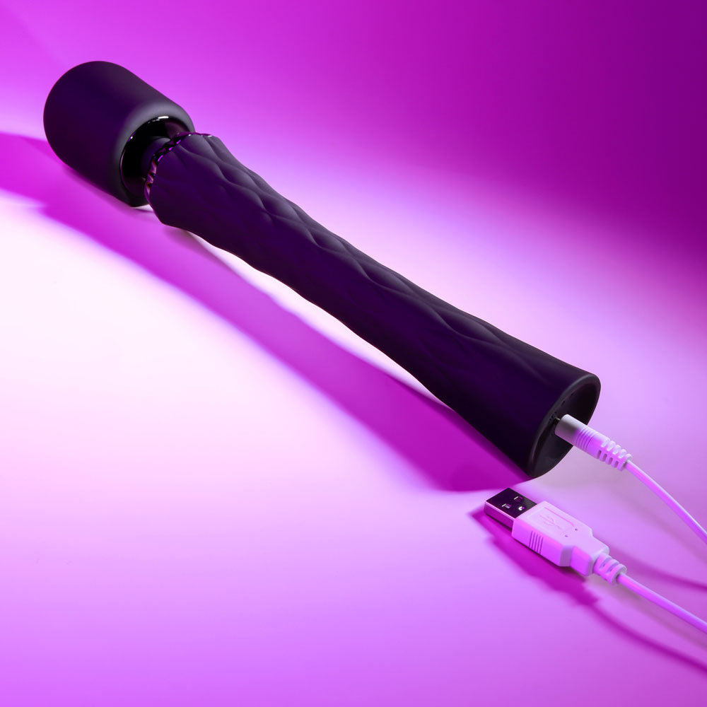 Black handheld device with a USB cable on a purple background