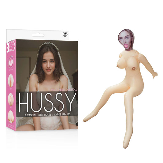 Hussy Gwen. The pink doll held in a hand against a white background.