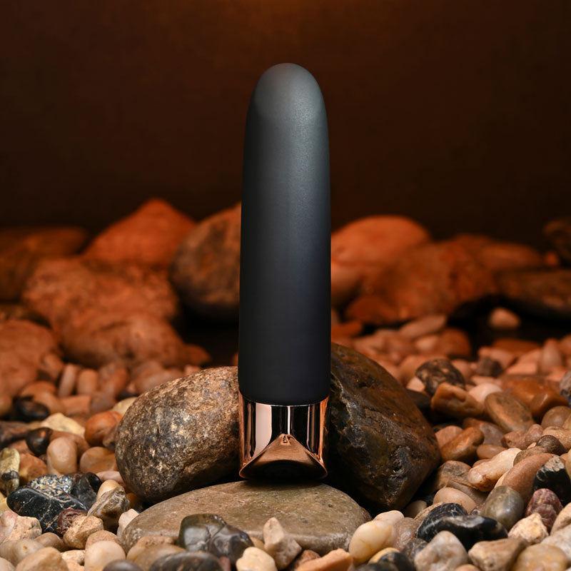 Black and rose gold device on a bed of rocks with a warm brown background