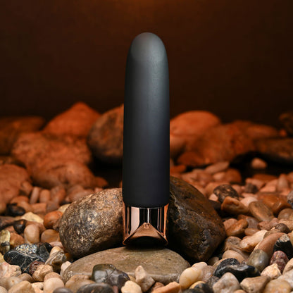 Black and rose gold device on a bed of rocks with a warm brown background