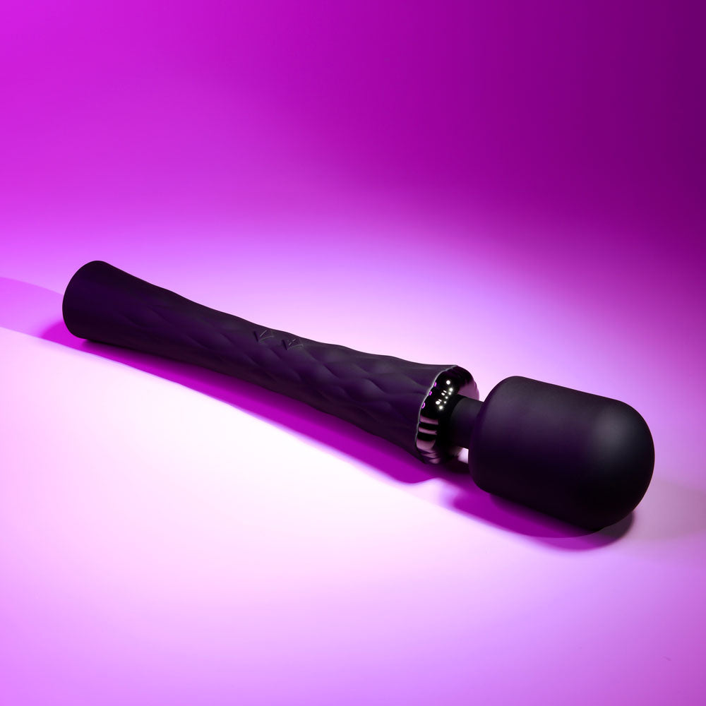 Black handheld massager on a pink gradient background