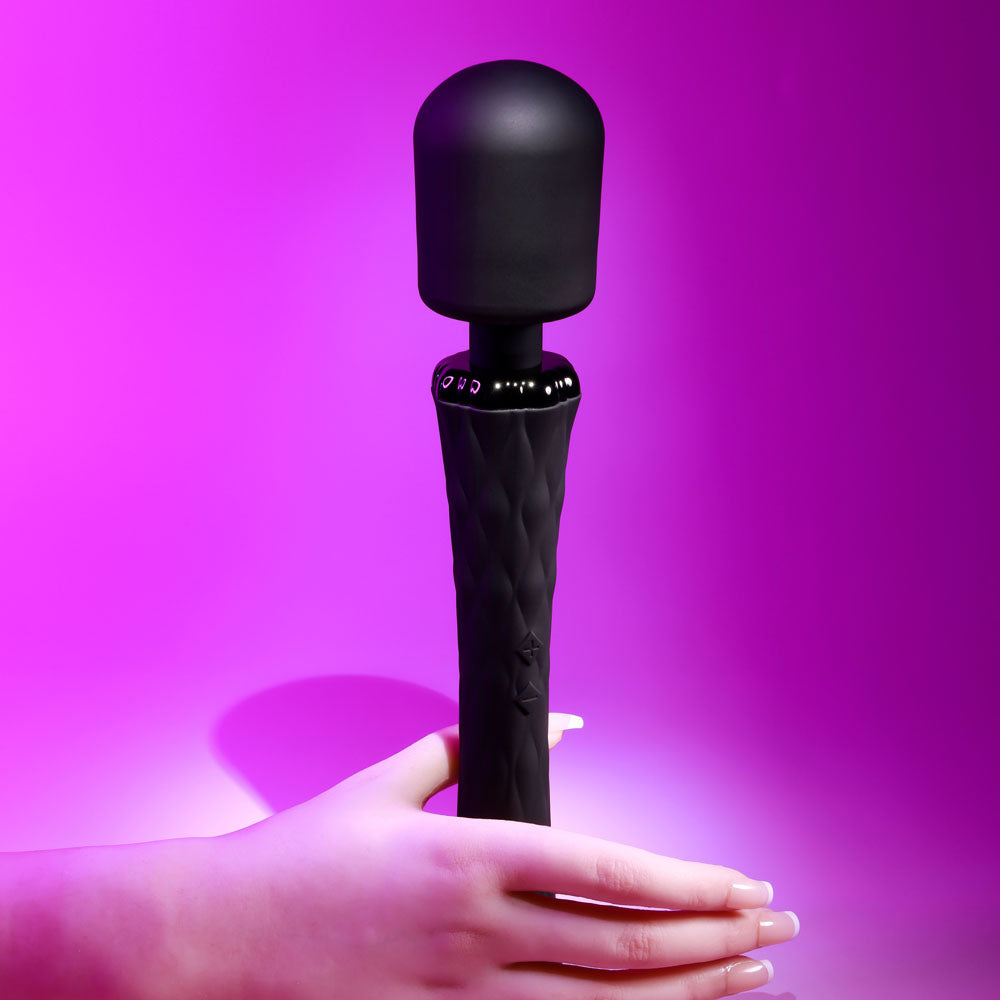 Black handheld device held by a hand against a purple background