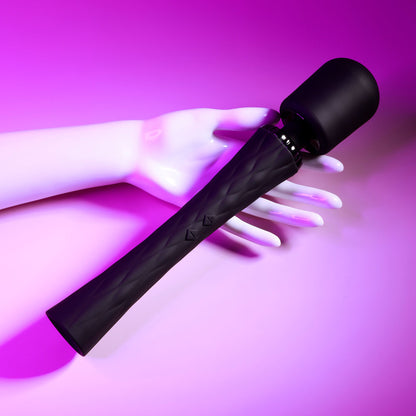 Black hair straightener held by a hand against a pink background