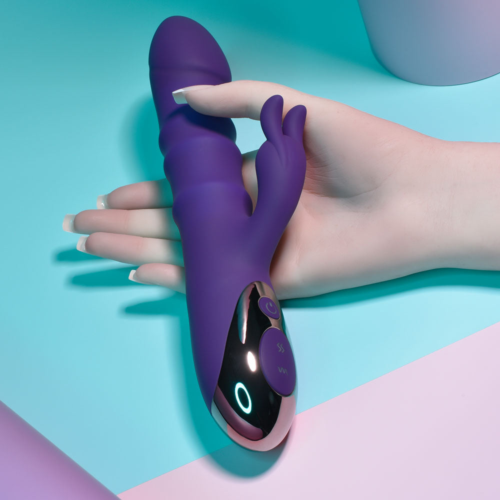 Purple handheld electronic device held by a hand on a colorful background