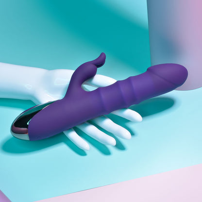 Purple and silver handheld massager on a white hand against a teal background