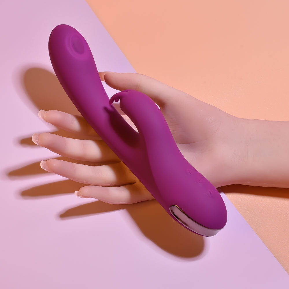 Hand holding a purple electronic device against a pink and orange background