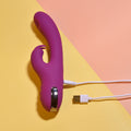 Purple electronic device with USB cable on a yellow and pink background