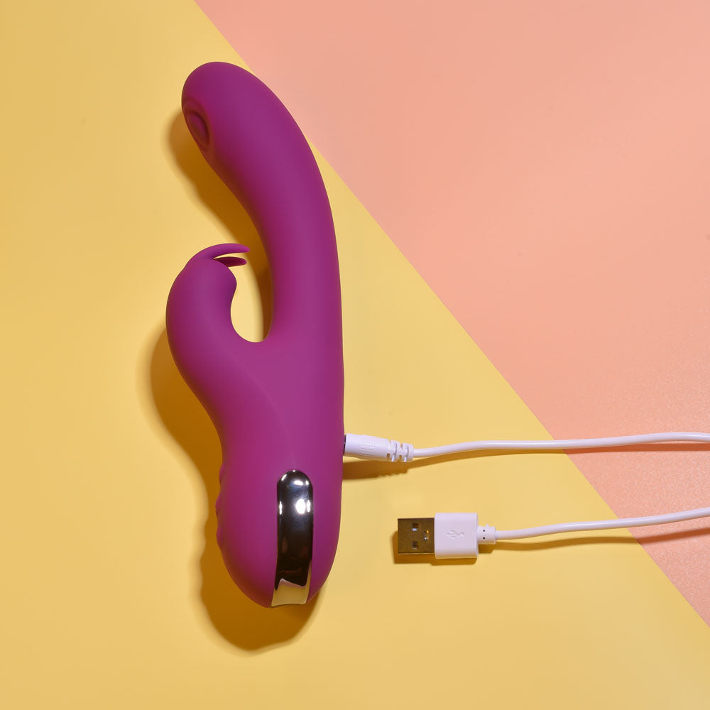 Purple electronic device with USB cable on a yellow and pink background