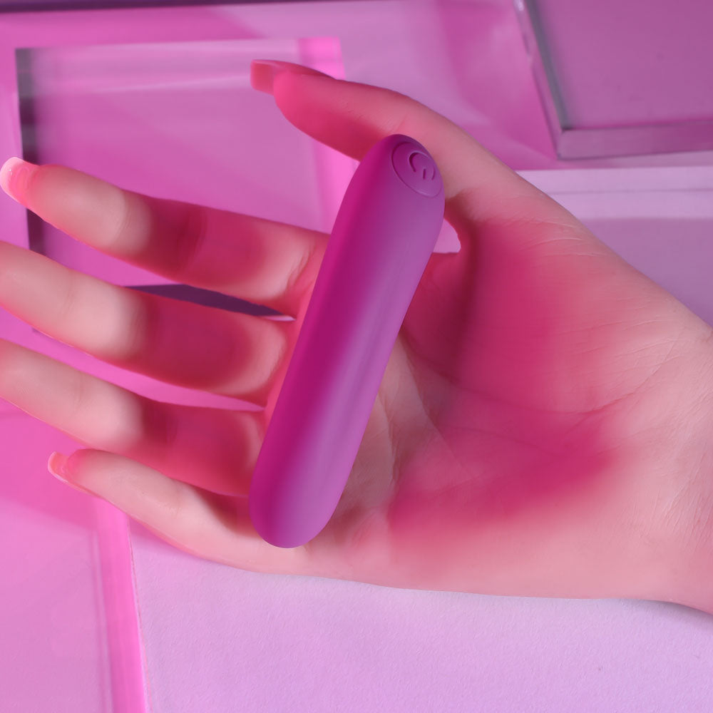 Hand holding a purple electronic device against a pink background