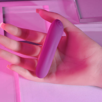 Hand holding a purple electronic device against a pink background