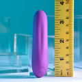 Purple cylindrical object next to a yellow ruler on a blue background
