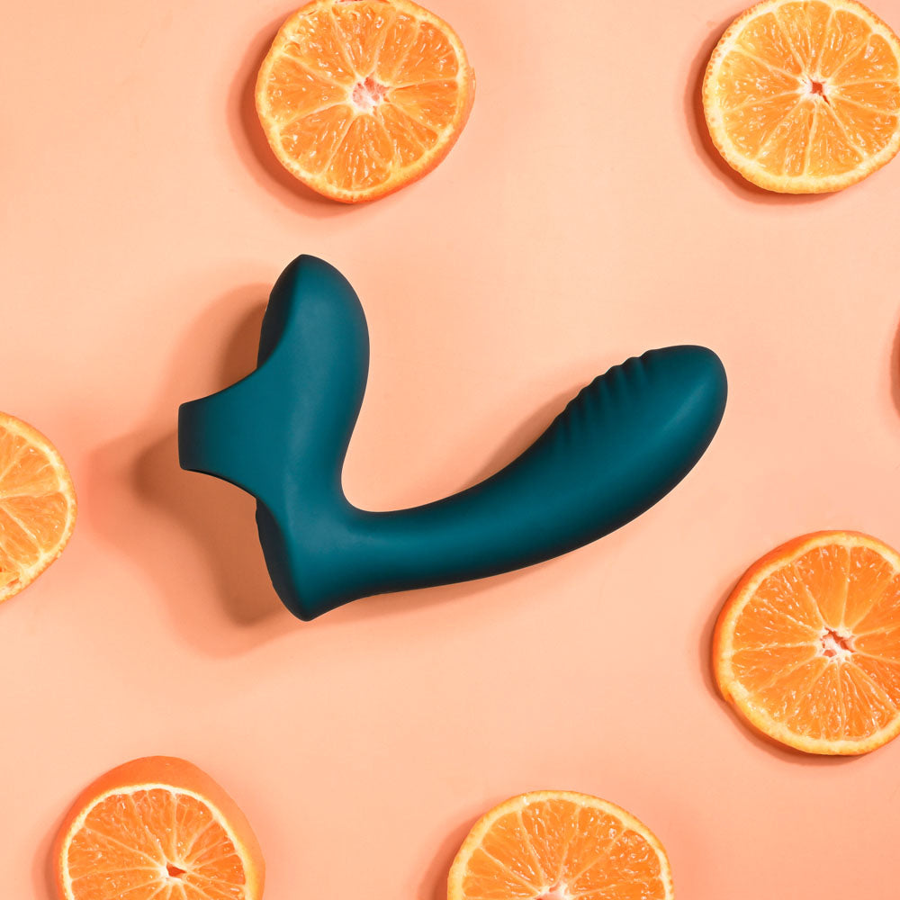 Teal silicone sleeve on a pink background with sliced oranges.