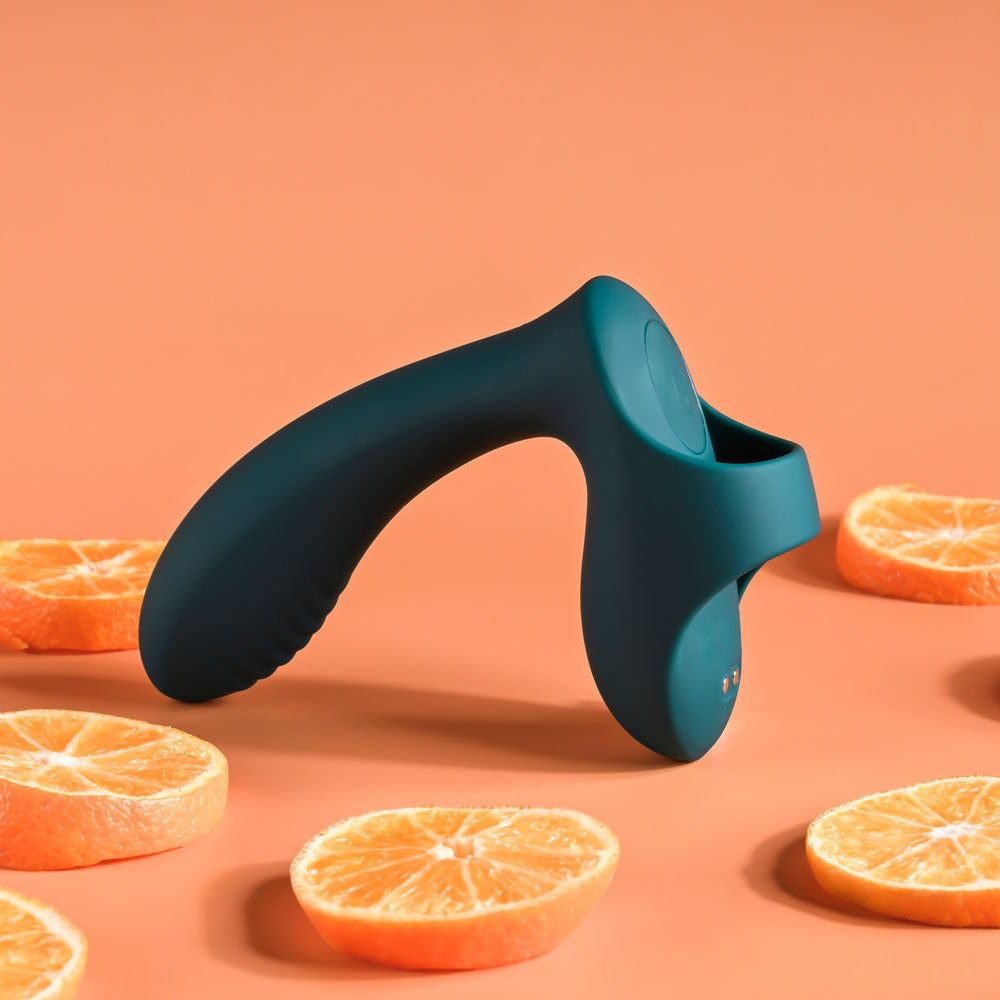Blue manual juicer surrounded by sliced oranges on a peach background