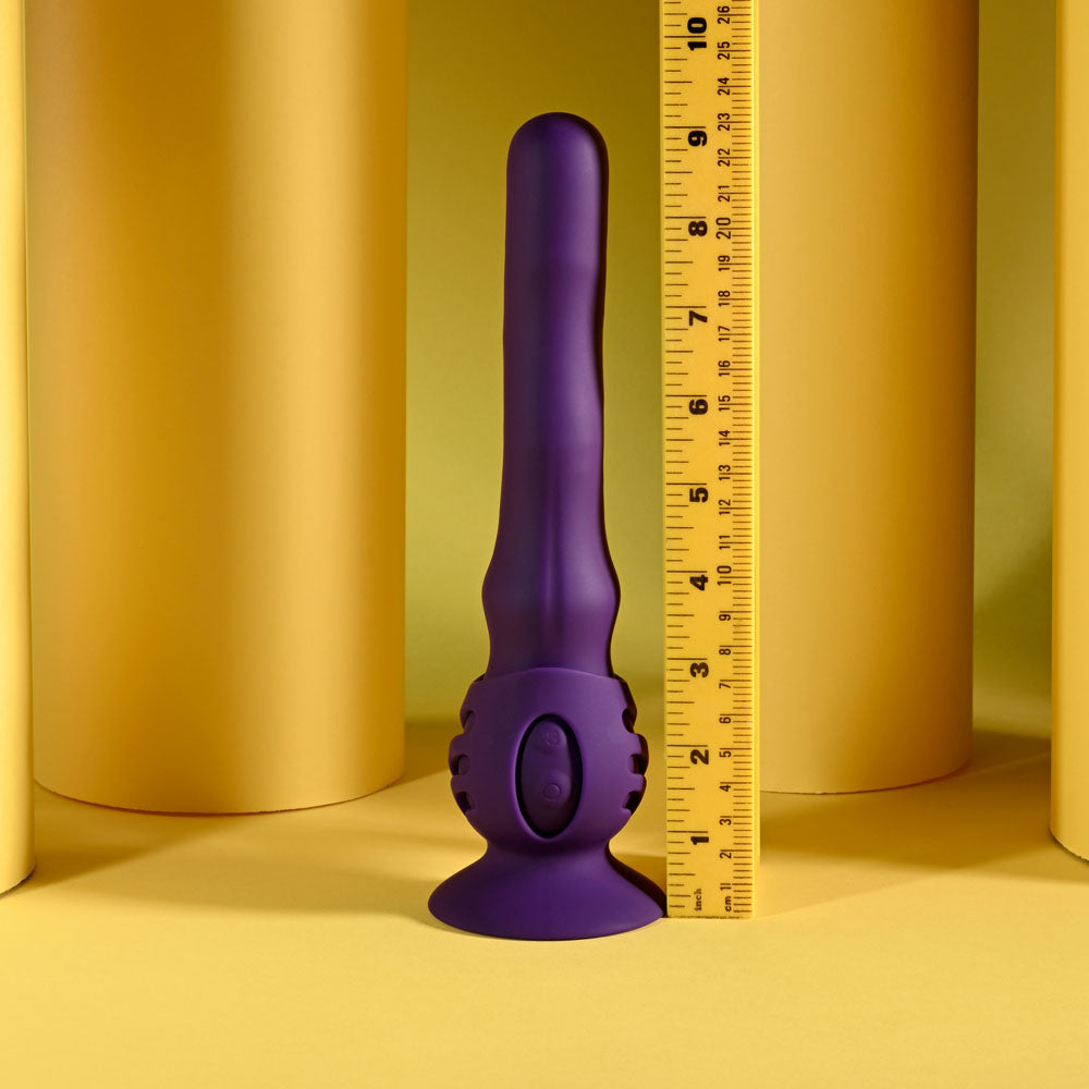 Purple cylindrical object with a textured base on a yellow background with a ruler for scale.