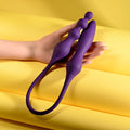 Purple silicone tool held by a hand on a yellow background