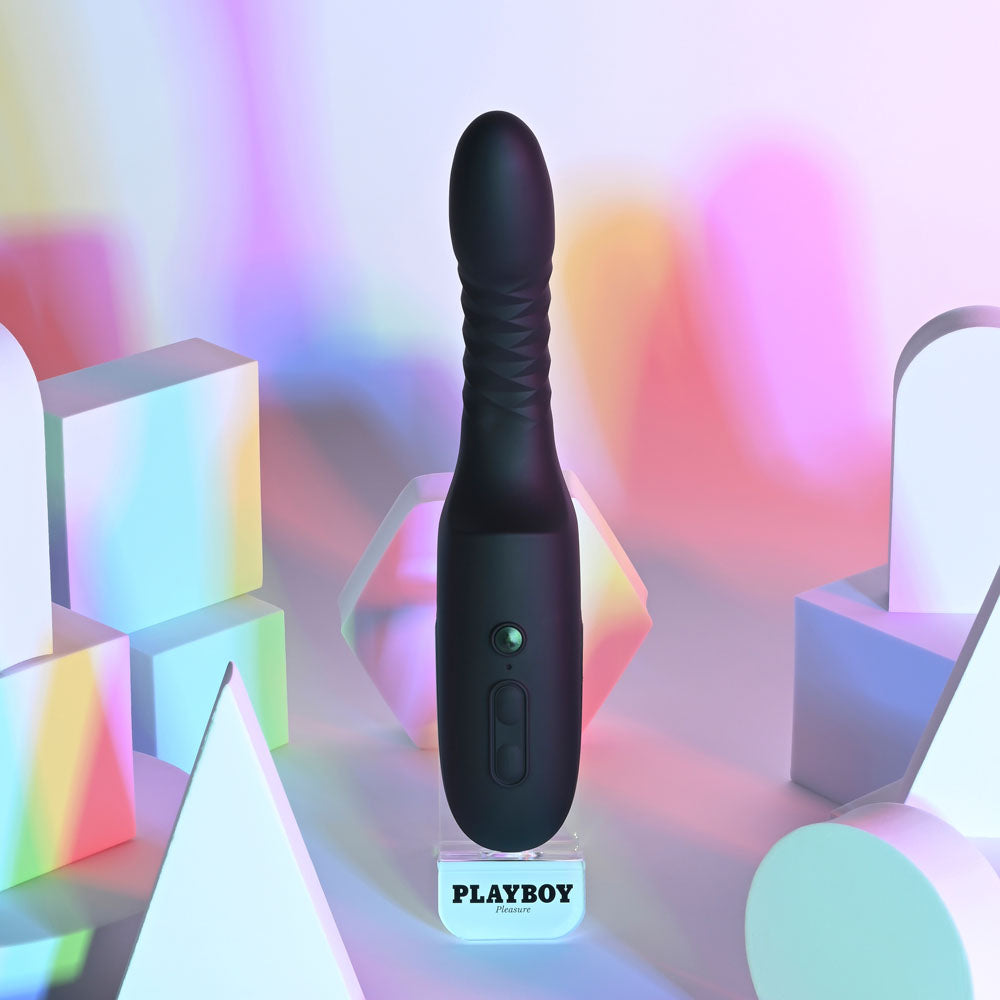 Black electronic device on a stand with 'Playboy' branding against a colorful geometric background