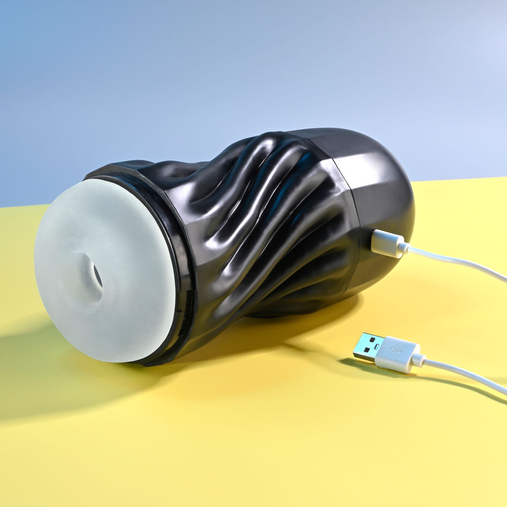 Black and white electronic device with USB cable on a yellow surface