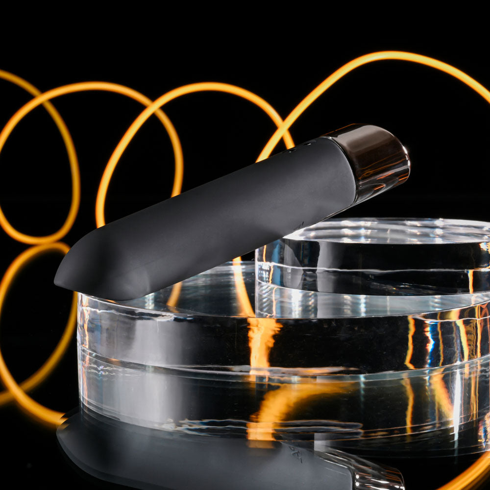 Black electronic device on a clear stand with glowing yellow circles in the background