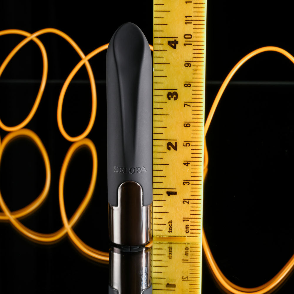 Black and silver tool with a tape measure showing its length against a dark background with orange circular patterns.