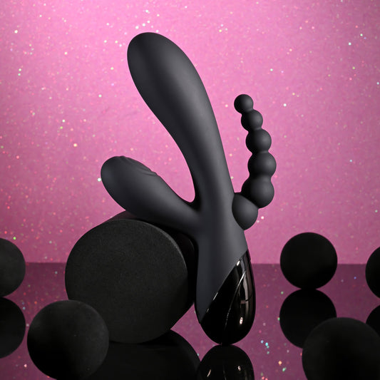 Black abstract sculpture on a pink reflective surface