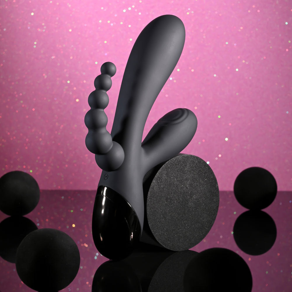 Black silicone butt plug on a pink glittery background