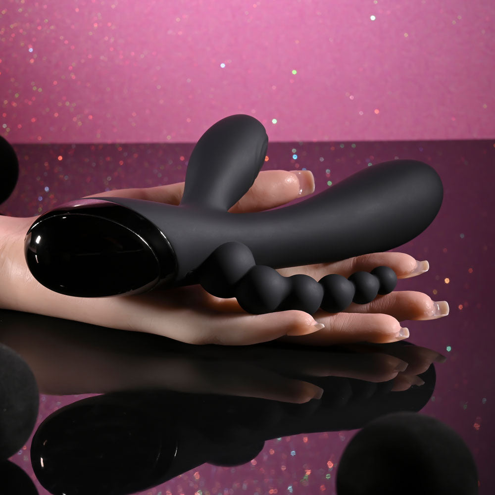 Black flexible tool held in hands against a pink and purple gradient background
