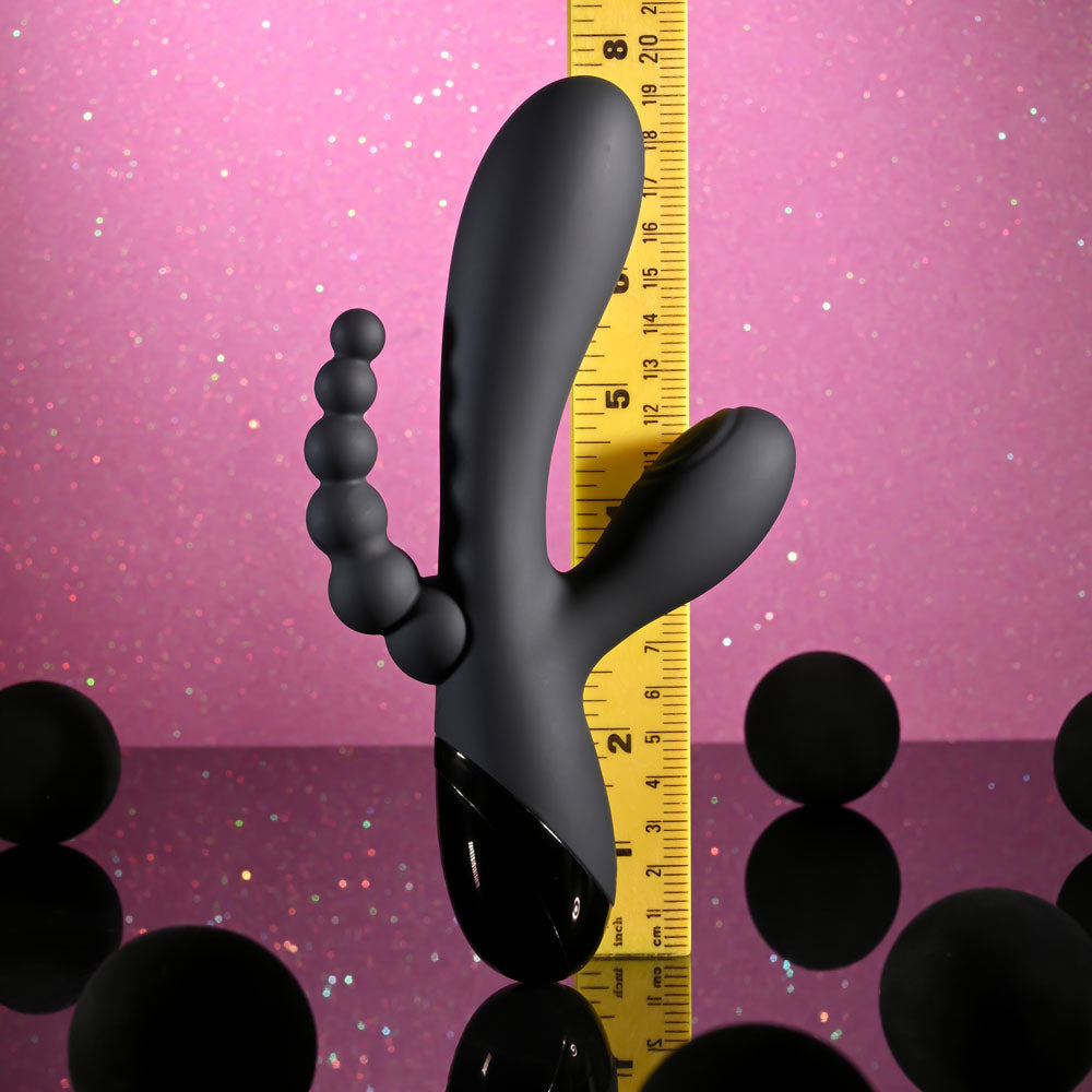 Black massage tool with measurement scale on a pink and purple gradient background